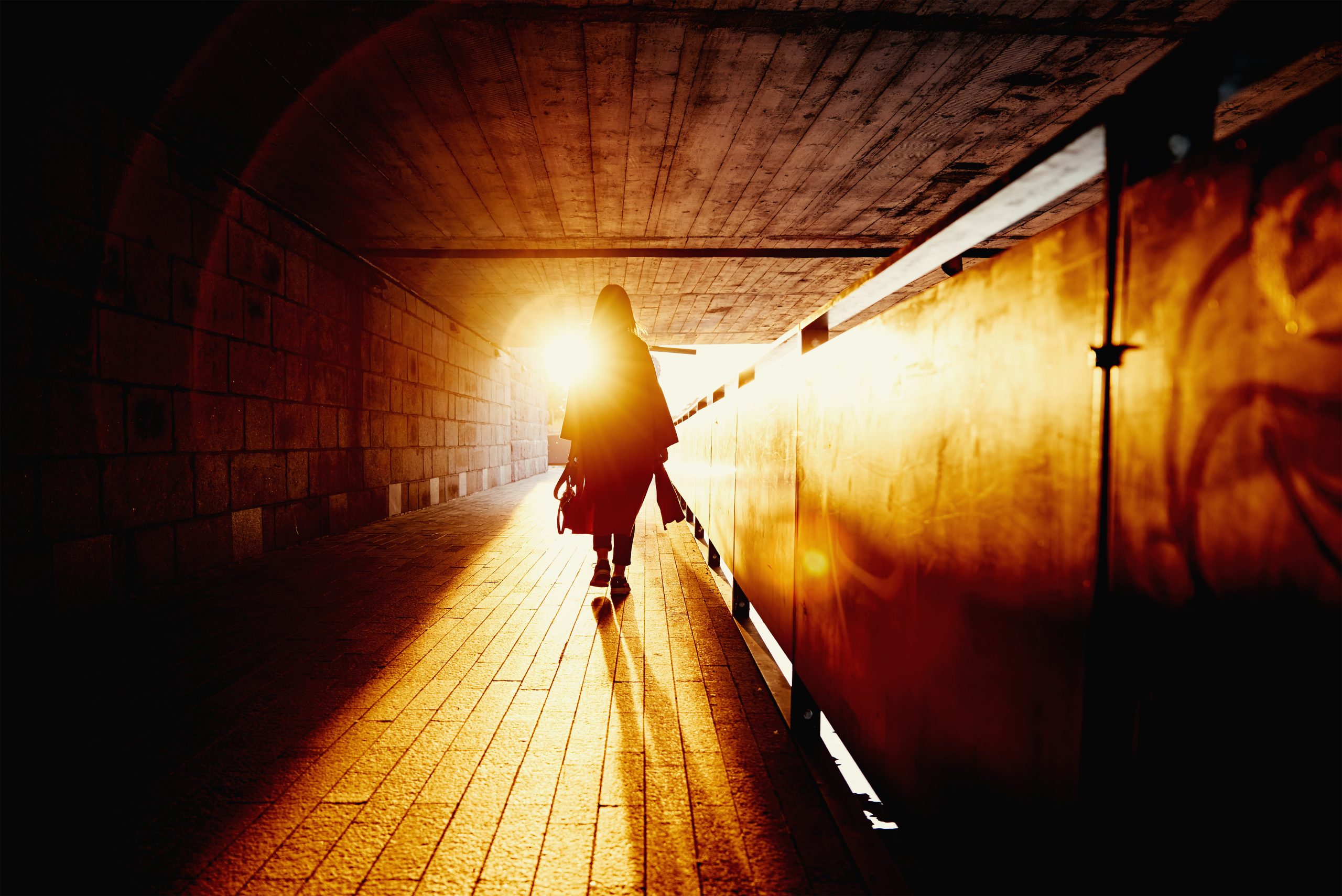 Woman walking alone through dark tunnel